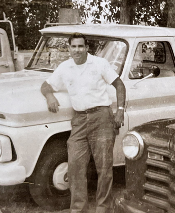 Tom Sr. standing in front of work trucks